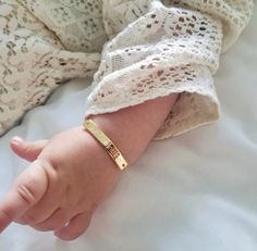 a small child's hand with a gold bracelet on top of it, laying down