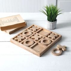 a wooden tic - tac toe game set next to a potted plant