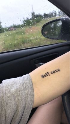 a person with a small tattoo on their arm sitting in a car