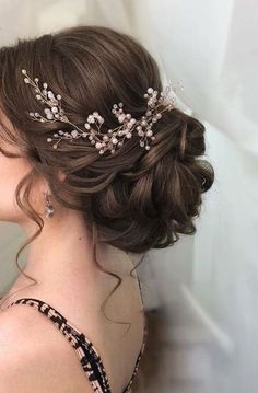 a woman wearing a bridal hair comb with flowers on it's head, in front of a white wall