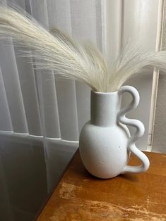 a white vase sitting on top of a wooden table