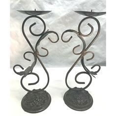 two metal candlesticks sitting next to each other on top of a white surface