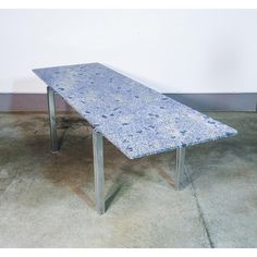 a blue table sitting on top of a cement floor next to a white wall in an empty room