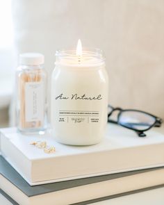 a candle sitting on top of a book next to eyeglasses and a pair of glasses