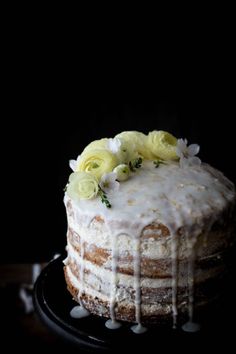 a cake with white frosting and flowers on top is sitting on a black plate