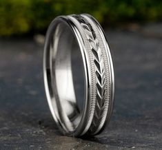 two wedding bands with braiding on them are sitting on the ground in front of some bushes