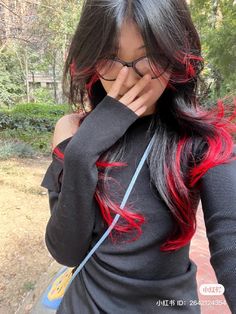 a woman with long black hair and red streaks on her face is posing for the camera