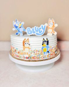 a white cake with sprinkles and cartoon characters on it's top