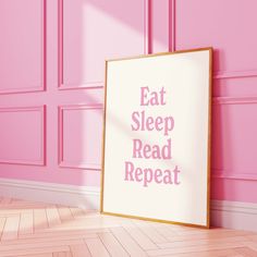 a pink room with a framed poster saying eat sleep read repeat on the floor next to it