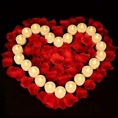 a heart shaped arrangement with candles in it