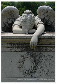 an angel statue sitting on top of a cement wall