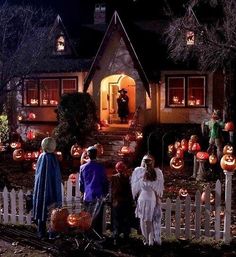 a group of people standing in front of a house decorated for halloween