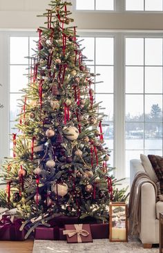 a decorated christmas tree in a living room with red and white ribbons on the top