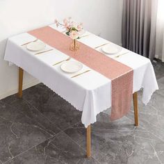 a white table with pink and gold trim on it, next to a vase filled with flowers