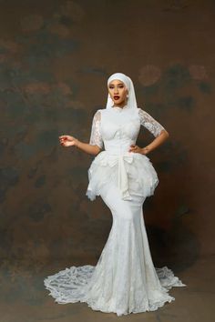 a woman in a white dress and veil posing for the camera with her hands on her hips