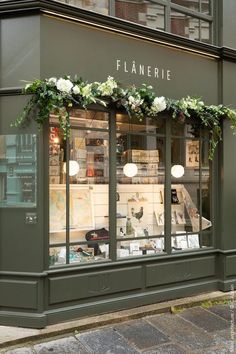 a store front with flowers in the window and on the side of the building that says flanerie