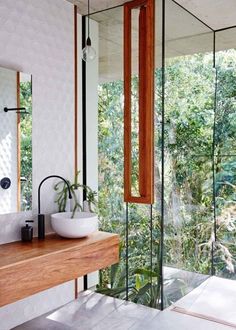 a modern bathroom with glass walls and wood accents