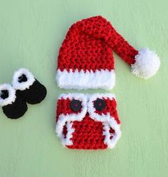 a crocheted santa hat and pair of eyeballs on a green surface with a white pom - pom