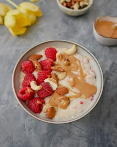 a bowl filled with yogurt, nuts and raspberries