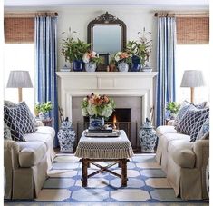 a living room filled with furniture and a fire place in front of a mirror on the wall