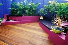 a wooden deck with plants and benches on it