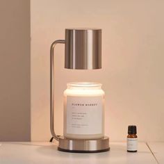 a candle and an essential oil bottle on a white countertop next to a silver lamp