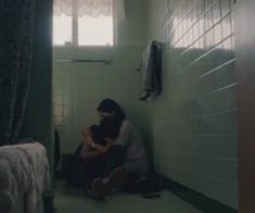 a person sitting on the floor in a room with green walls and white tile floors