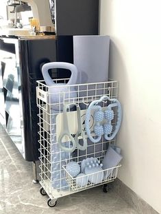 a white wire basket with scissors and other items in it next to a black refrigerator