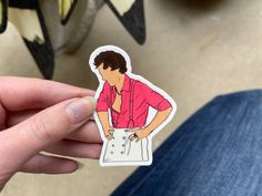 a person holding up a sticker with a man in a pink shirt on it