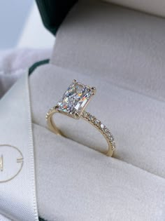 a diamond ring sitting on top of a white cloth covered cushion in a gift box