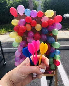 a person holding several colorful balloons in their hand