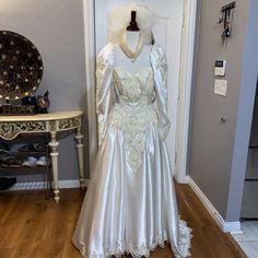 a wedding dress is displayed in front of a mirror on the floor next to a mannequin