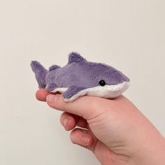 a hand holding a small stuffed toy shark