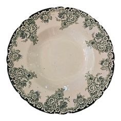 a white and green plate with black trimmings on the rim, decorated with flowers