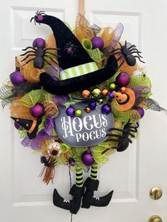 a halloween wreath hanging on the front door decorated with witch hats, pumpkins and decorations