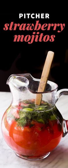 a pitcher filled with tomatoes and herbs on top of a table