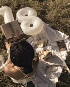 a woman laying in the grass reading a book and wearing an inflatable ring