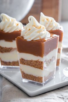 three desserts are sitting on a plate with white frosting and chocolate toppings