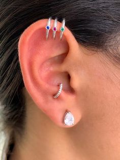 a woman with three different colored stones on her ear and two piercings in the middle