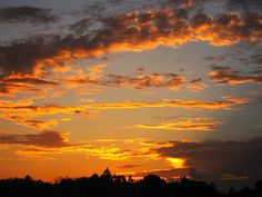 the sun is setting behind some clouds in the sky