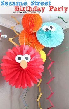 the sesame street birthday party is complete with paper fans and tissue pom poms