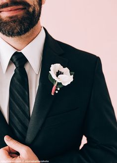 a man wearing a suit and tie with a boutonniere on his lapel