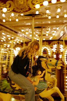 a woman on a merry go round with lights in the background and an illuminated carousel behind her