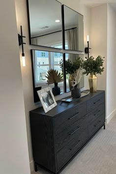 a black dresser topped with a mirror and vases