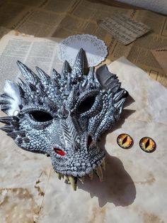 a dragon mask sitting on top of a piece of paper next to two small eyeballs