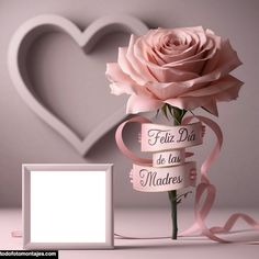 a pink rose with ribbon around it next to a white box and heart shaped object