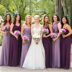 a group of women standing next to each other wearing purple dresses and holding bouquets