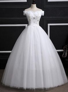 a white ball gown on display in front of a black door with the dress hanging down