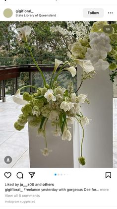 two white vases filled with flowers on top of a table