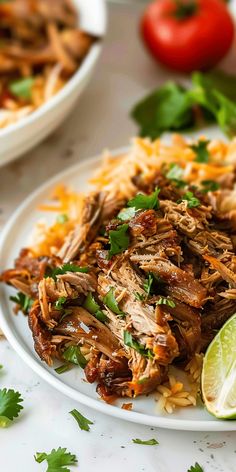 shredded pork with cilantro and lime on a white plate